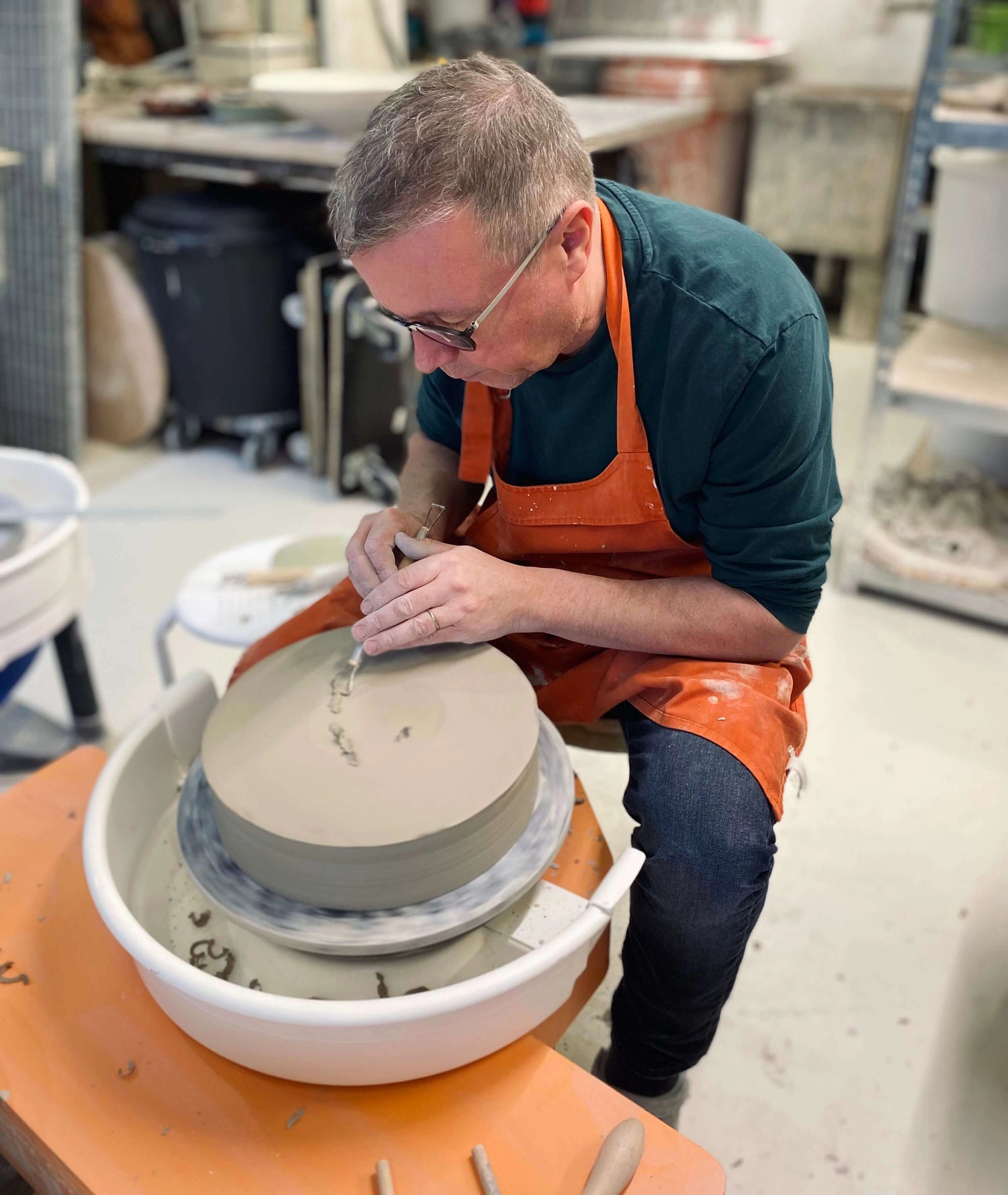 Notre céramiste réalise un plat unique en céramique avec son tour et ses outils dans l'atelier à Fosses-la-ville. 